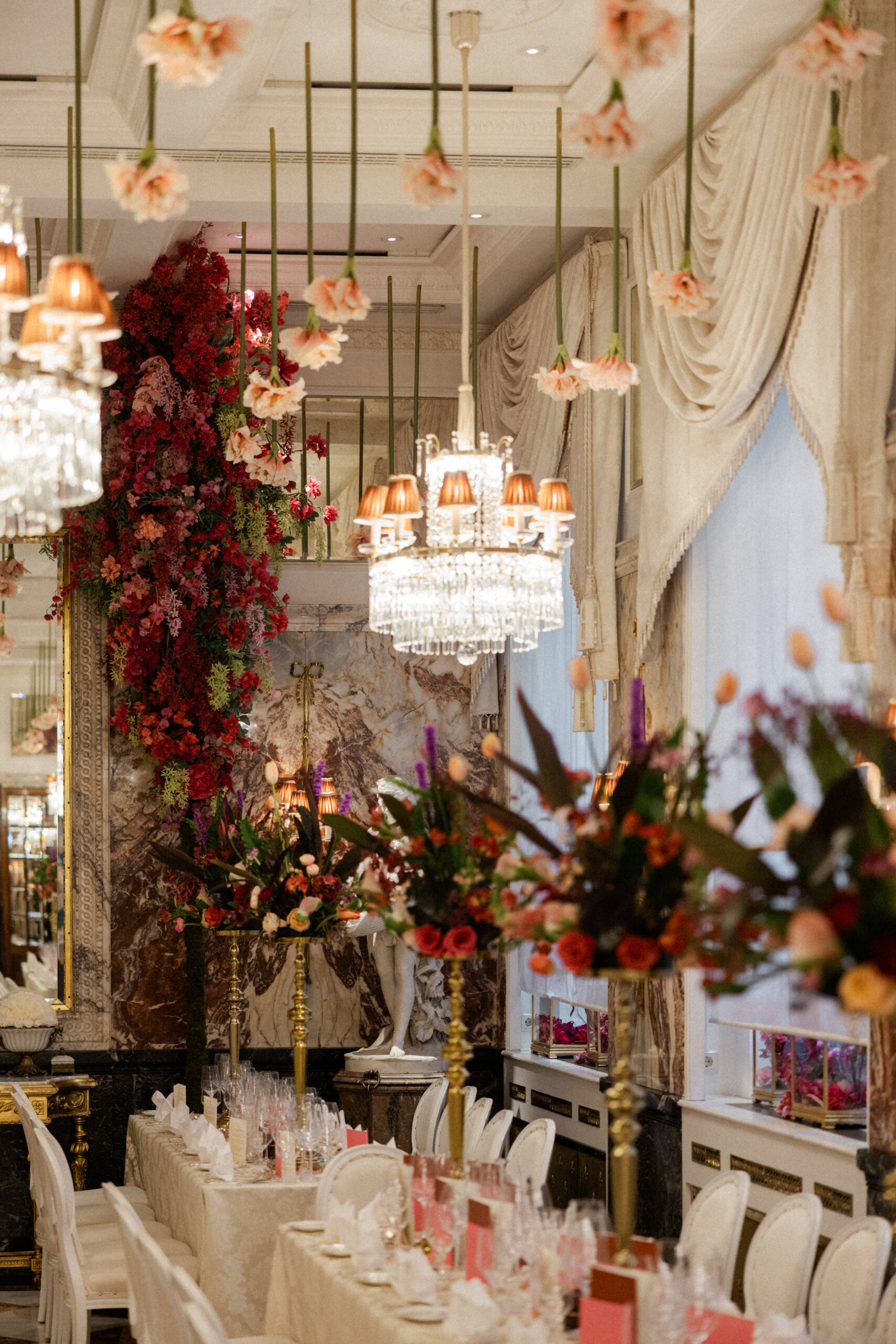 Festlich dekorierter Marmorsaal im Hotel Sacher Wien mit langen Tafeln, Kristallleuchtern und üppigen Blumenarrangements.
