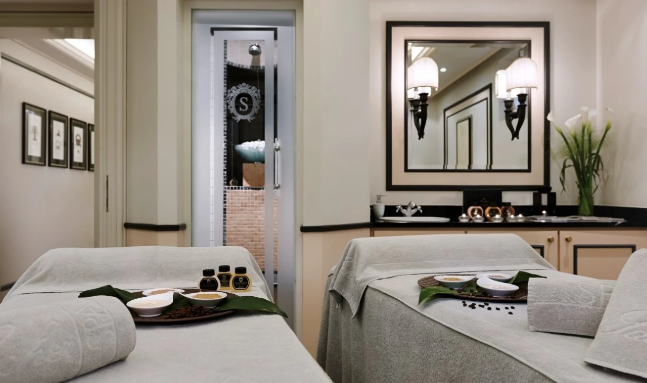 Ein eleganter Spa-Behandlungsraum mit zwei vorbereiteten Liegen, abgestimmt in hellen Naturtönen. Edle Pflegeprodukte, frische Blüten und die detailverliebte Einrichtung schaffen eine ruhige, luxuriöse Atmosphäre für eine entspannende Auszeit zu zweit.