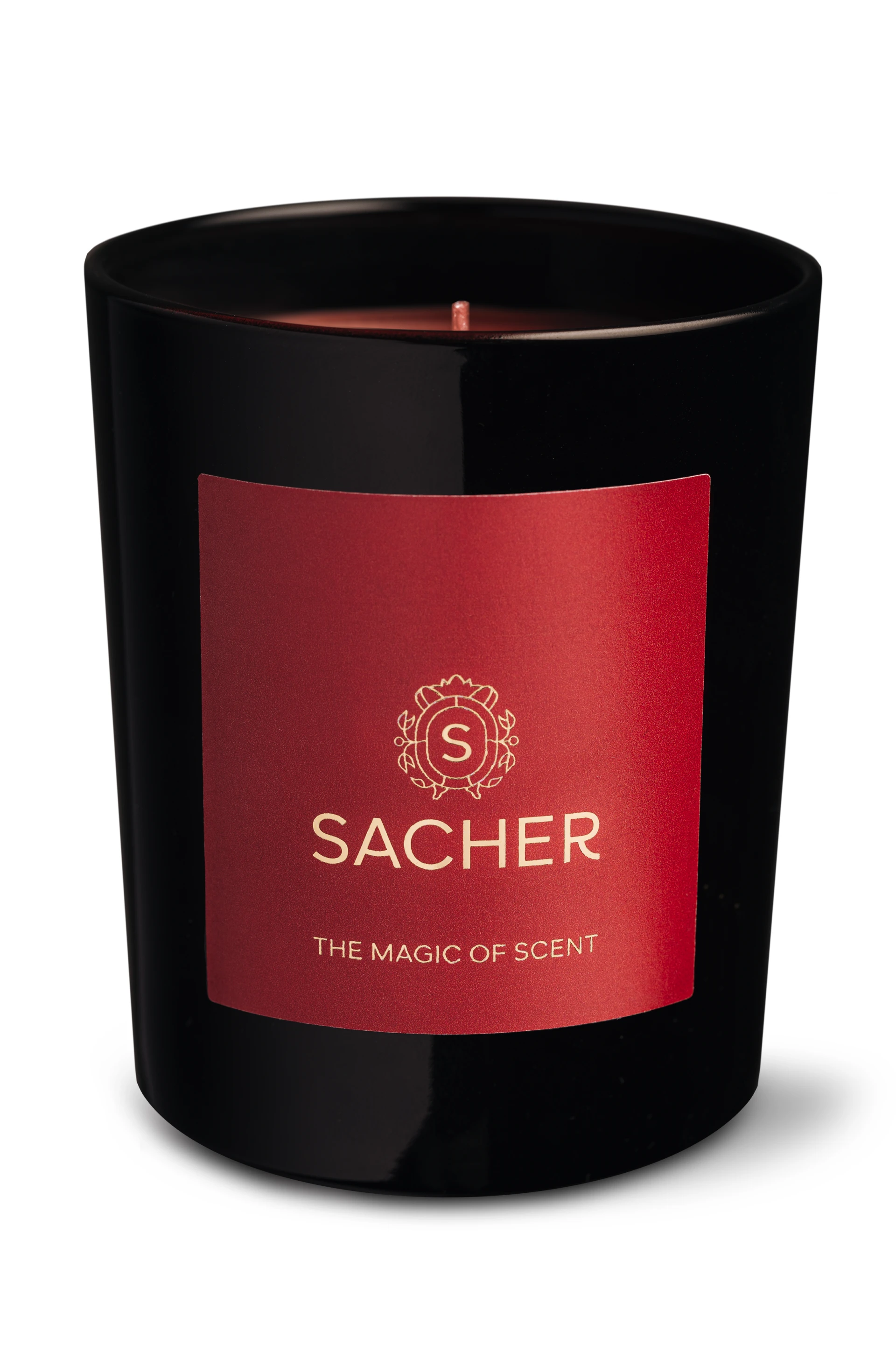 Schwarzes Glas mit rotem Etikett und goldener Sacher-Aufschrift „THE MAGIC OF SCENT“, freigestellt auf weißem Hintergrund, mit sichtbar unentzündetem Docht.