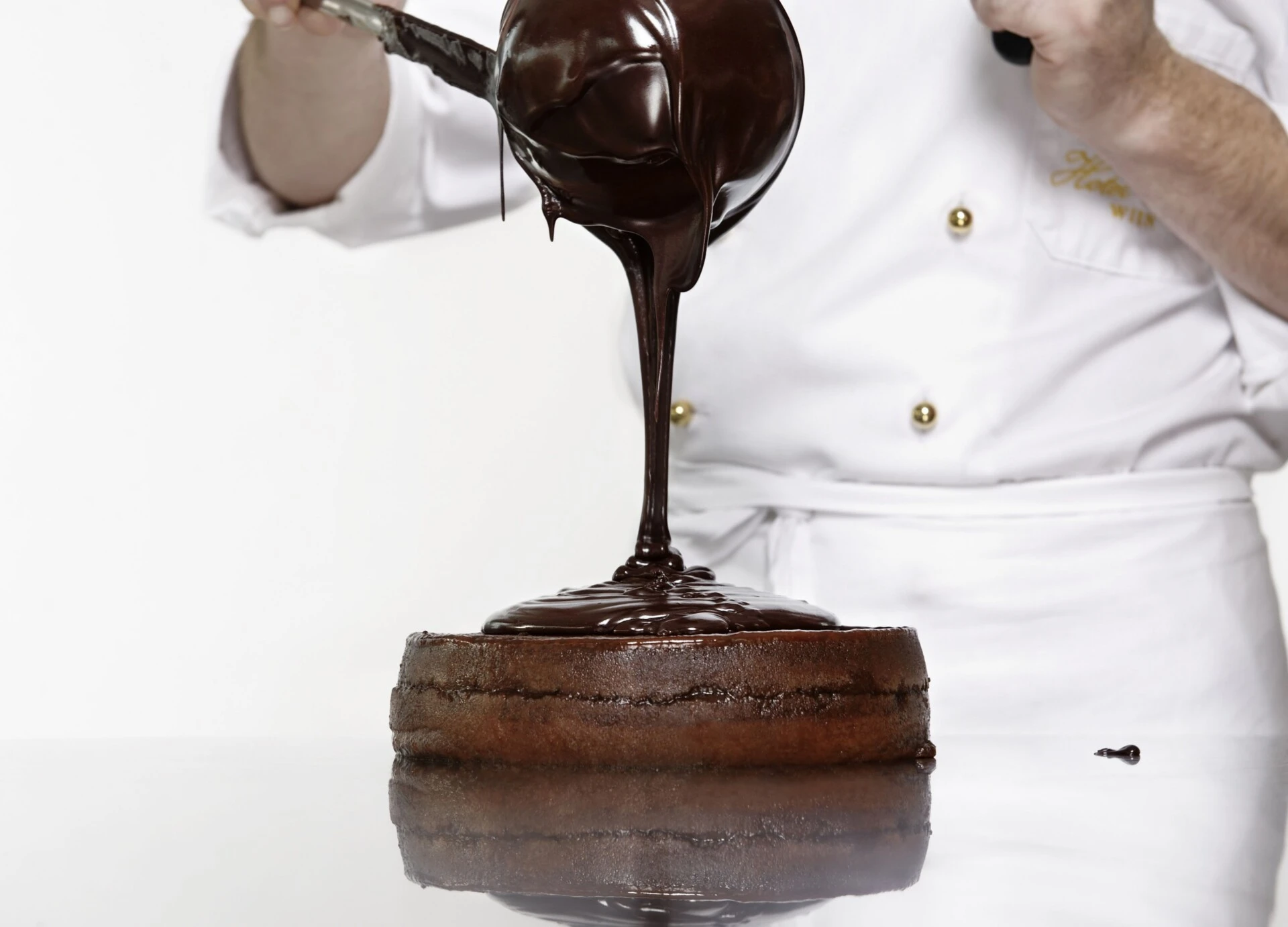 Flüssige Schokolade wird großzügig über eine Original Sacher-Torte gegossen.