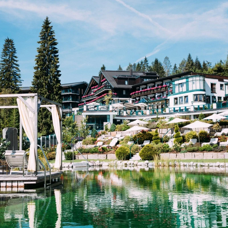 Ein idyllisches Hotelresort inmitten der Natur bietet luxuriöse Unterkünfte mit großzügigen Balkonen und bunter Blumendekoration.