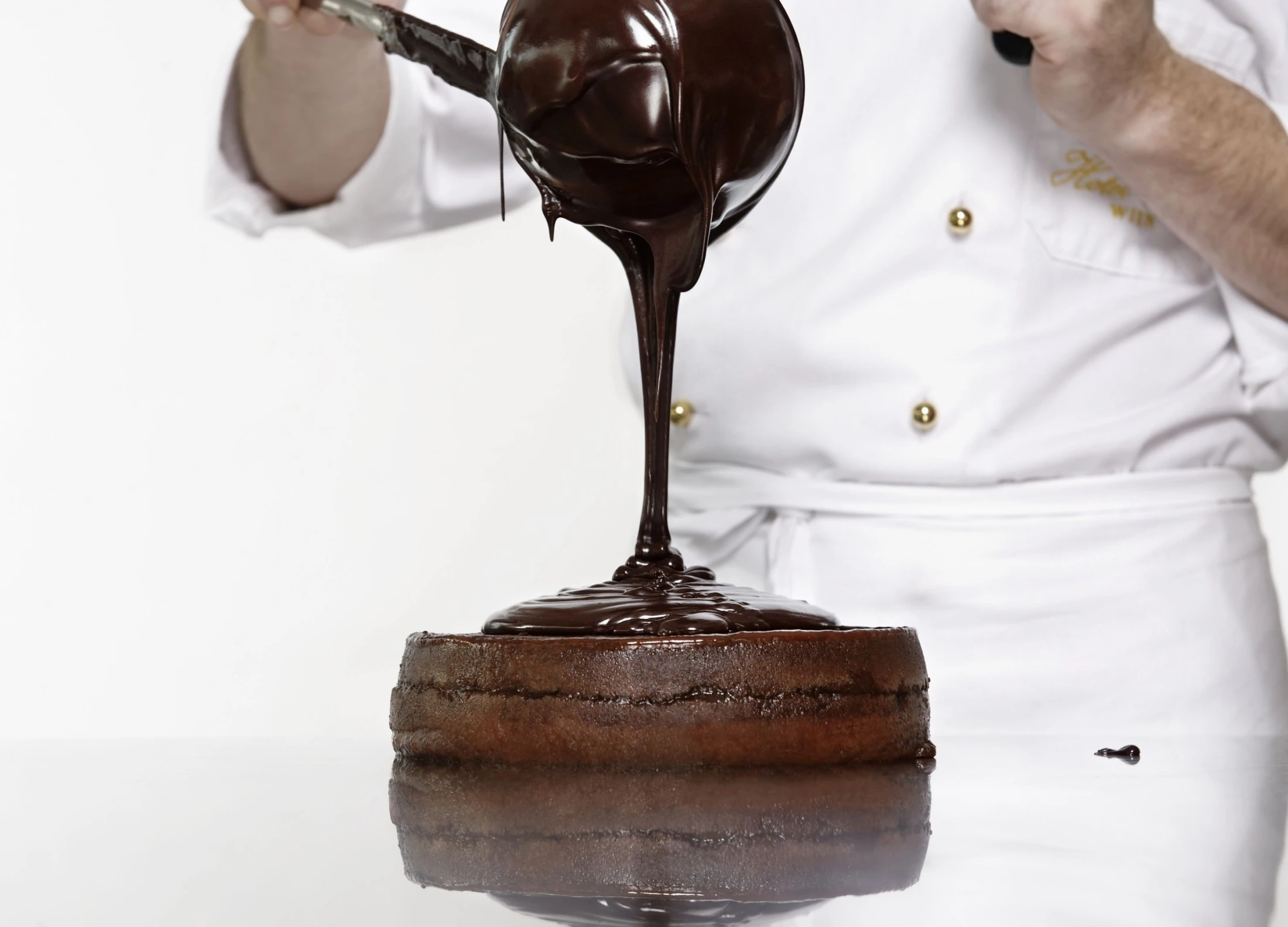 Flüssige Schokolade wird großzügig über eine Original Sacher-Torte gegossen.