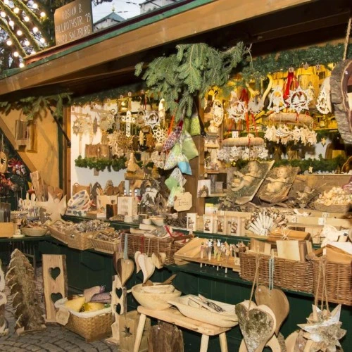 Festlich dekorierter Weihnachtsmarktstand mit handgefertigtem Christbaumschmuck, Krippenfiguren und liebevollen Details aus Holz und Stroh.
