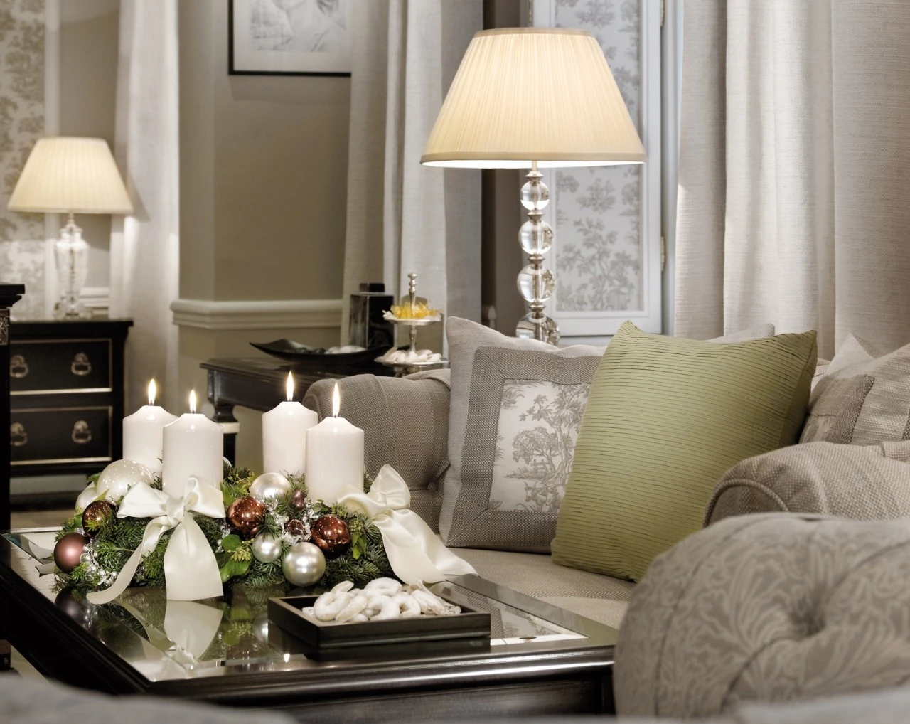 Elegant dekoriertes Wohnzimmer mit Adventskranz, brennenden Kerzen und weihnachtlichem Gebäck auf einem Couchtisch.