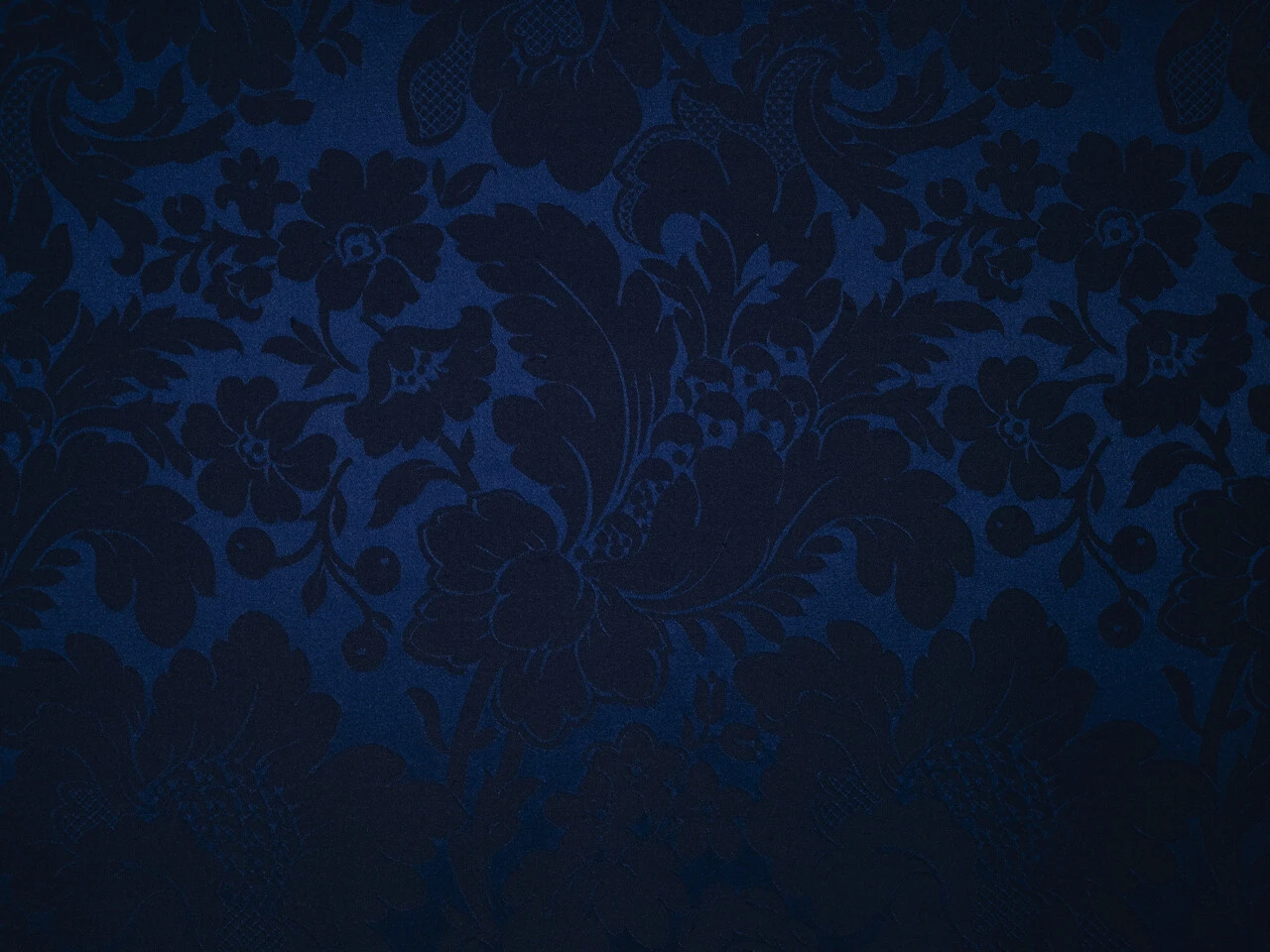 Ein tiefblauer, opulent gewebter Damaststoff mit floralen Ornamenten.