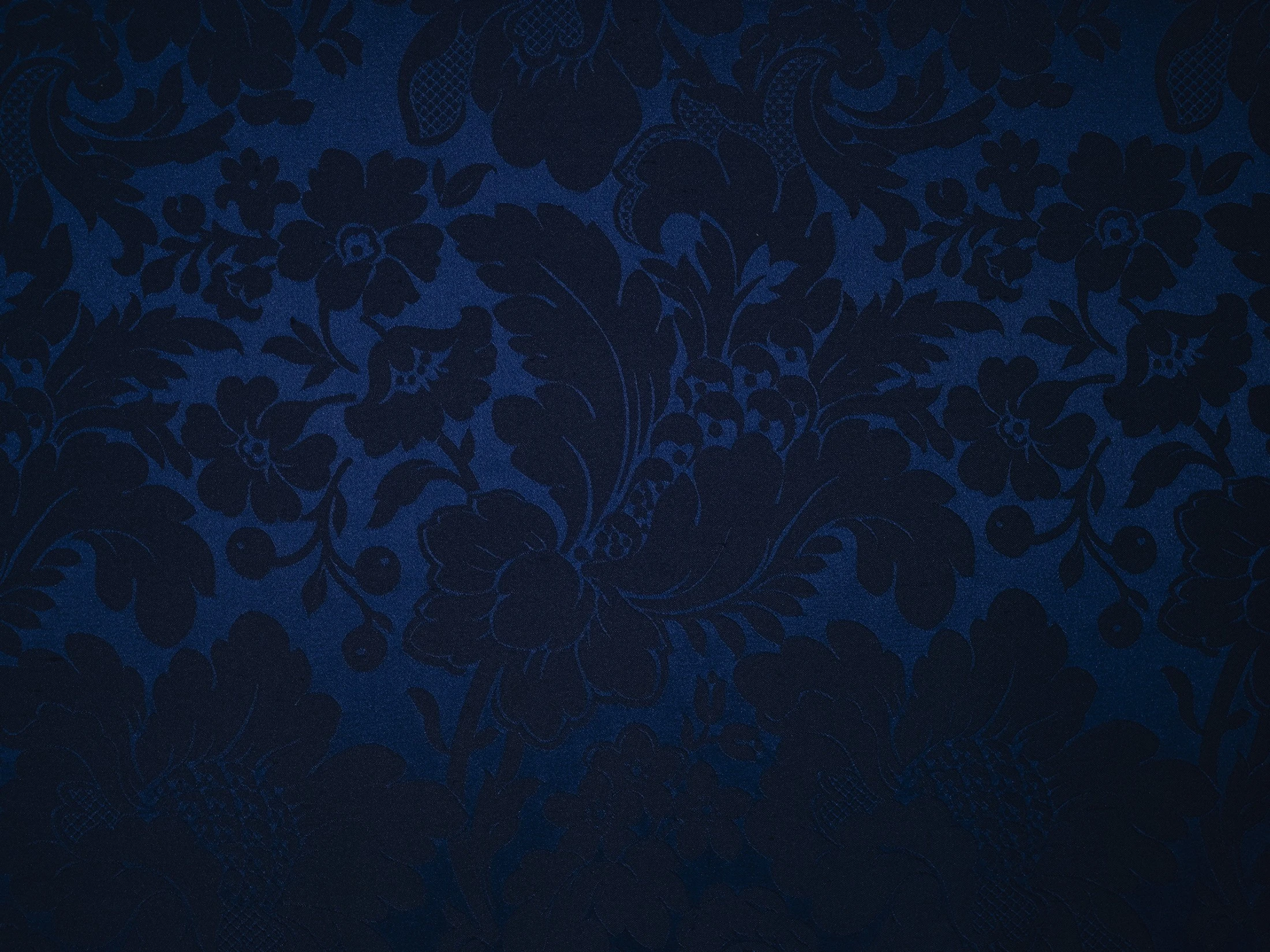 Ein tiefblauer, opulent gewebter Damaststoff mit floralen Ornamenten.