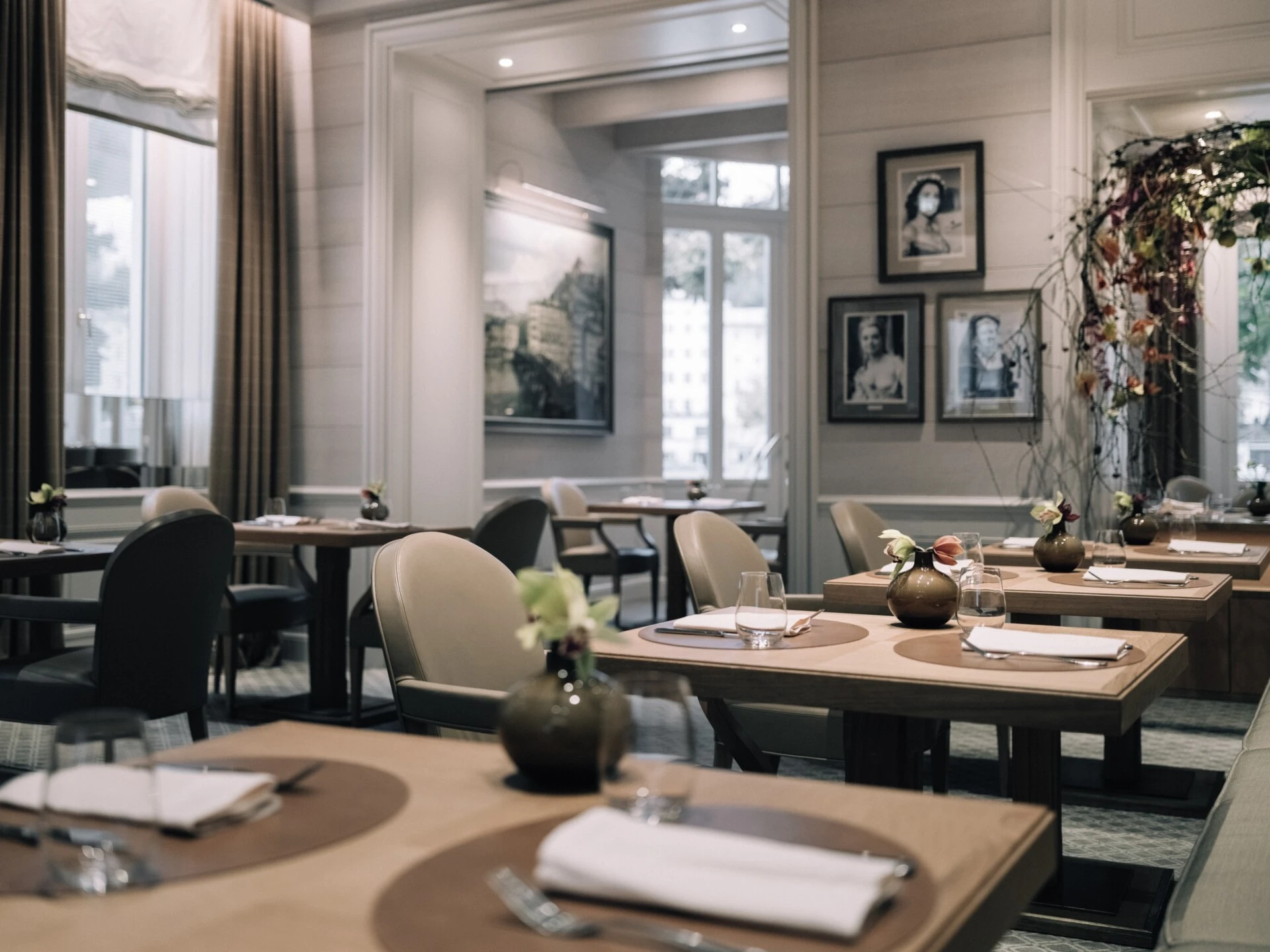 Helles, elegant eingerichtetes Restaurant mit modern-klassischem Stil. Die Möbel sind aus hellem Holz, kombiniert mit bequemen, hellgrauen Polsterstühlen. Große Fenster sorgen für viel Tageslicht und einen schönen Ausblick.