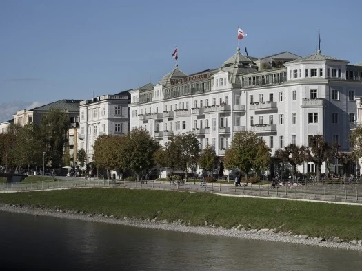 Hotel Sacher Salzburg, Gebäude Hotel Sacher Salzburg am Tag. Im Vordergrund sieht man die Salzach.