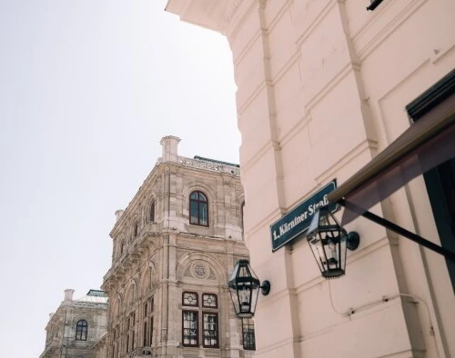 Wiener Staatsoper. Im Vordergrund ist ein Straßenschild mit der Aufschrift „Kärntner Straße“ zu sehen.