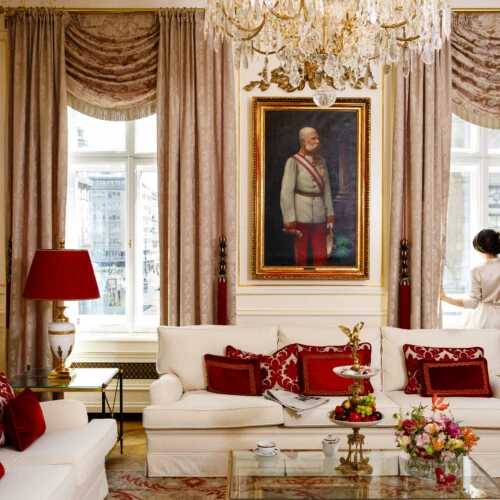 Wohnzimmer der Wiener Philharmoniker Suite mit Blick auf die Staatsoper, ausgestattet mit historischen Gemälden, edlen Vorhängen und prunkvollen Möbeln in Rot- und Goldtönen