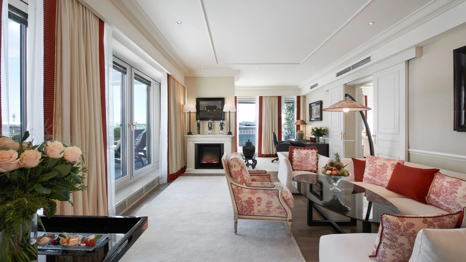 Das Wohnzimmer der Opera Penthouse Suite im Hotel Sacher Wien mit eleganter Sitzecke, gemütlichem Kamin und Zugang zur großzügigen Terrasse mit Blick über Wien