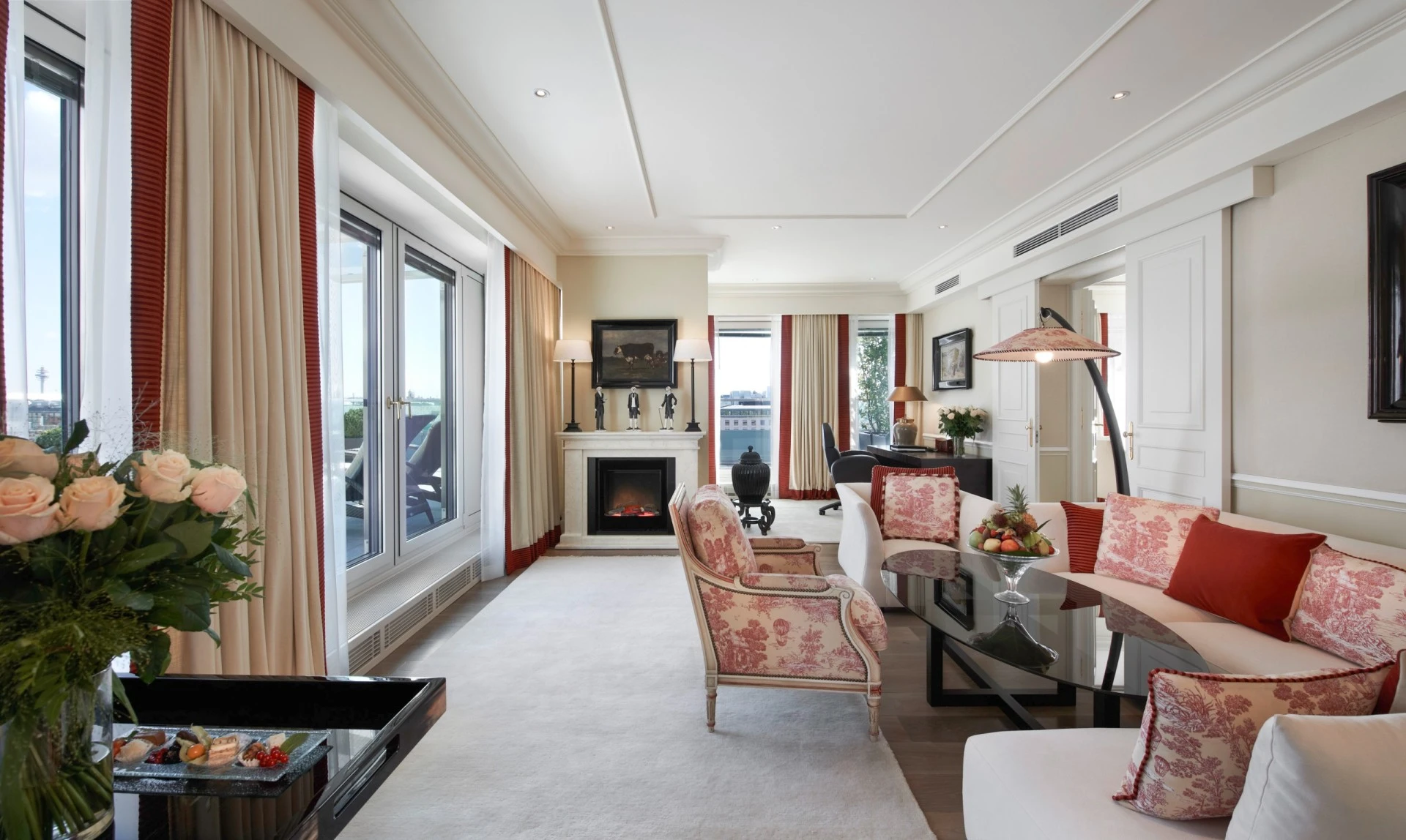 Das Wohnzimmer der Opera Penthouse Suite im Hotel Sacher Wien mit eleganter Sitzecke, gemütlichem Kamin und Zugang zur großzügigen Terrasse mit Blick über Wien