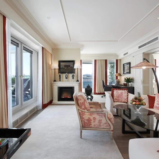 Das Wohnzimmer der Opera Penthouse Suite im Hotel Sacher Wien mit eleganter Sitzecke, gemütlichem Kamin und Zugang zur großzügigen Terrasse mit Blick über Wien