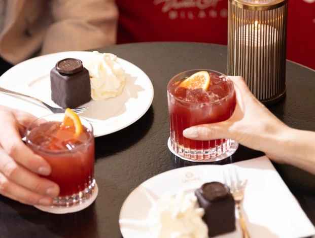 © Gregory Culbengan | www.adrianalmasan.com Zwei Original Sacher Würfel mit Schlagobers und Campari-Cocktails auf einem Tisch