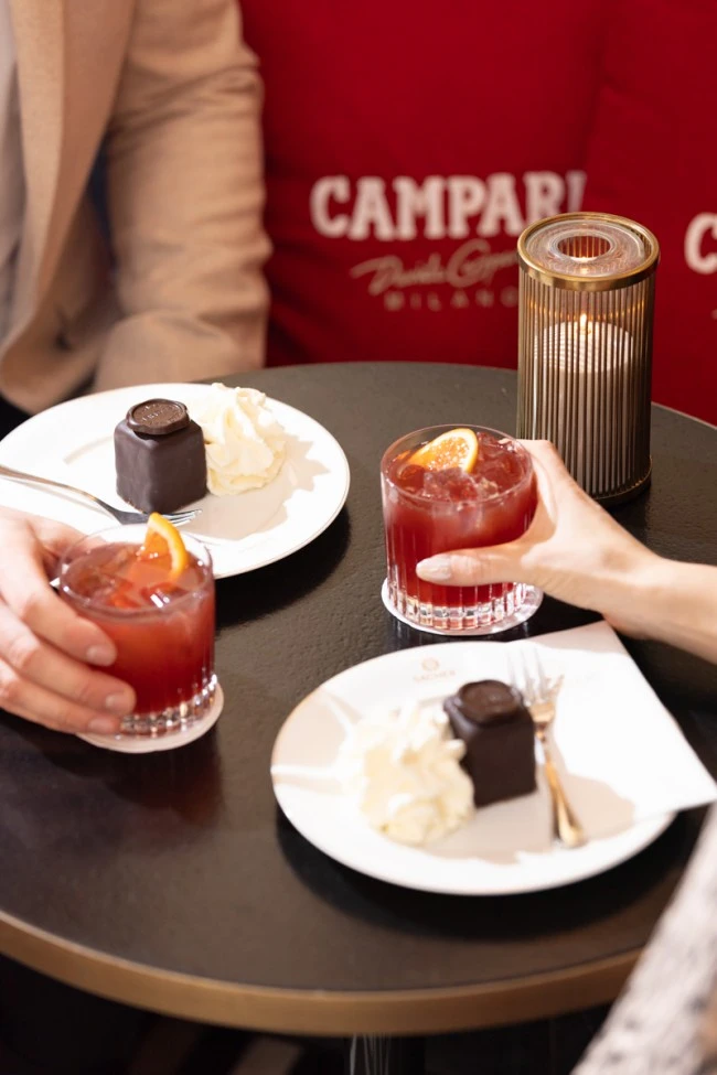 Zwei Original Sacher Würfel mit Schlagobers und Campari-Cocktails auf einem Tisch