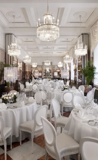 Großer Festsaal mit runden, weiß gedeckten Tischen, weißen Stühlen und zahlreichen Kristalllüstern.