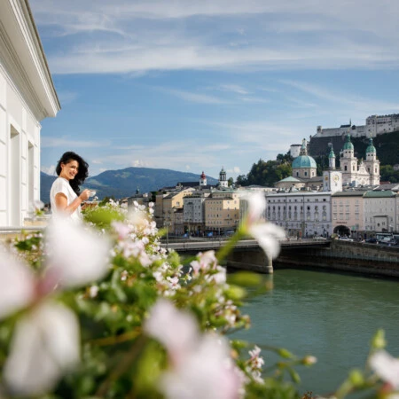 Genussvoller Moment auf dem Balkon mit Blick auf die Salzburger Altstadt und die Festung Hohensalzburg – Eleganz trifft Panorama.