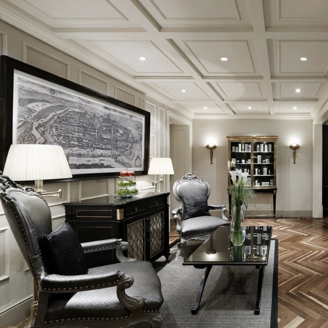 boutique-spa-hotel-sacher-vienna Spa Bereich Sacher Wien - Eleganter Lounge-Bereich mit historischen Sesseln, Wandkarte von Wien, Apfel-Dekoration und Pflegeprodukten in einer stilvollen Vitrine.