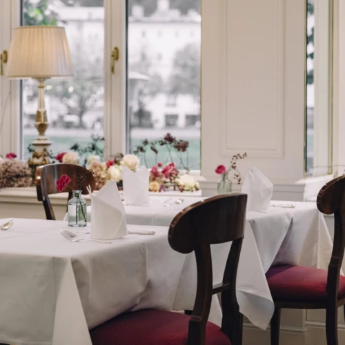 Gemütliches Event-Raum mit Blumenfensterbank, weißen Tischdecken und nostalgischen Tischlampen
