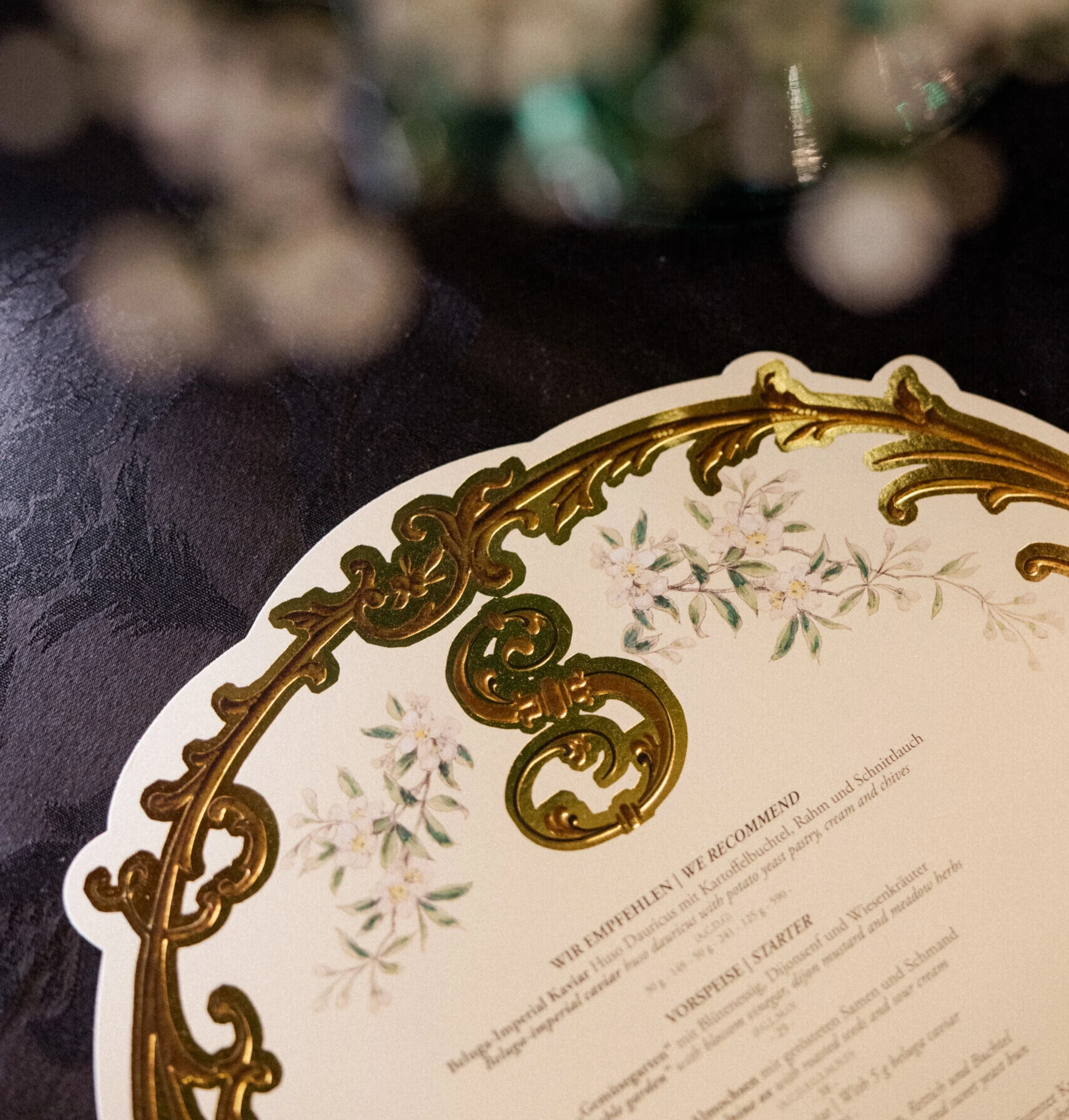 Nahaufnahme einer dekorativen Menükarte mit goldenen Ornamenten auf dem Tisch.