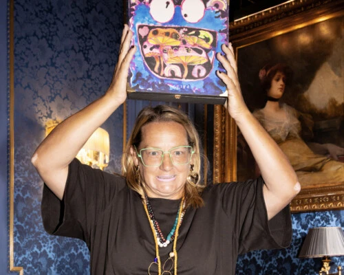 Künstlerin Katherine Bernhardt lächelt und hält die Limited Edition 2025 der Sacher-Torte