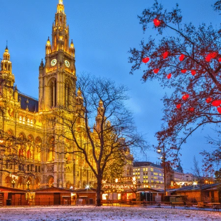 Wiener Rathaus erleuchtet mit festlichen Weihnachtslichtern und Marktständen in der Abenddämmerung