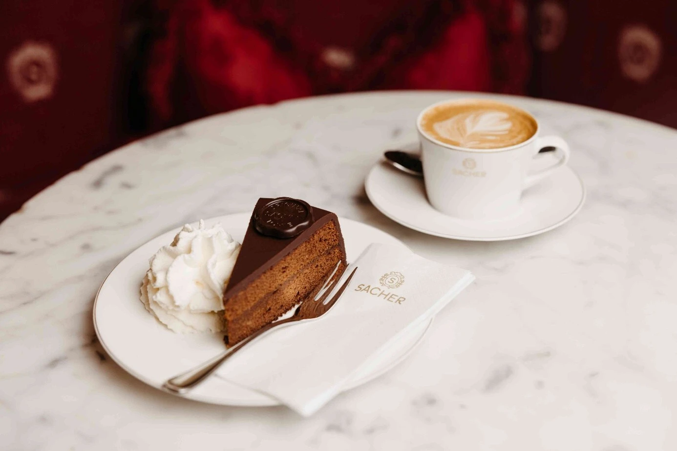 Original Sacher-Torte mit Schlagobers und Kaffee im Café Sacher Salzburg – österreichische Kuchenspezialität.