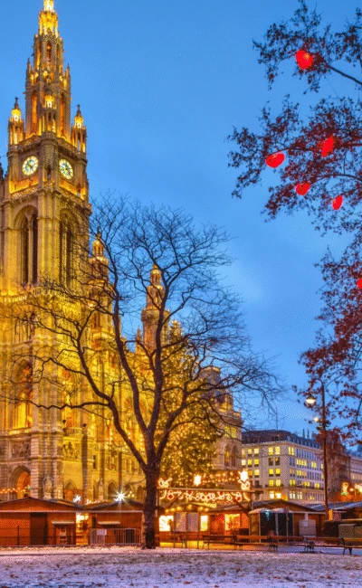 Wiener Rathaus erleuchtet mit festlichen Weihnachtslichtern und Marktständen in der Abenddämmerung
