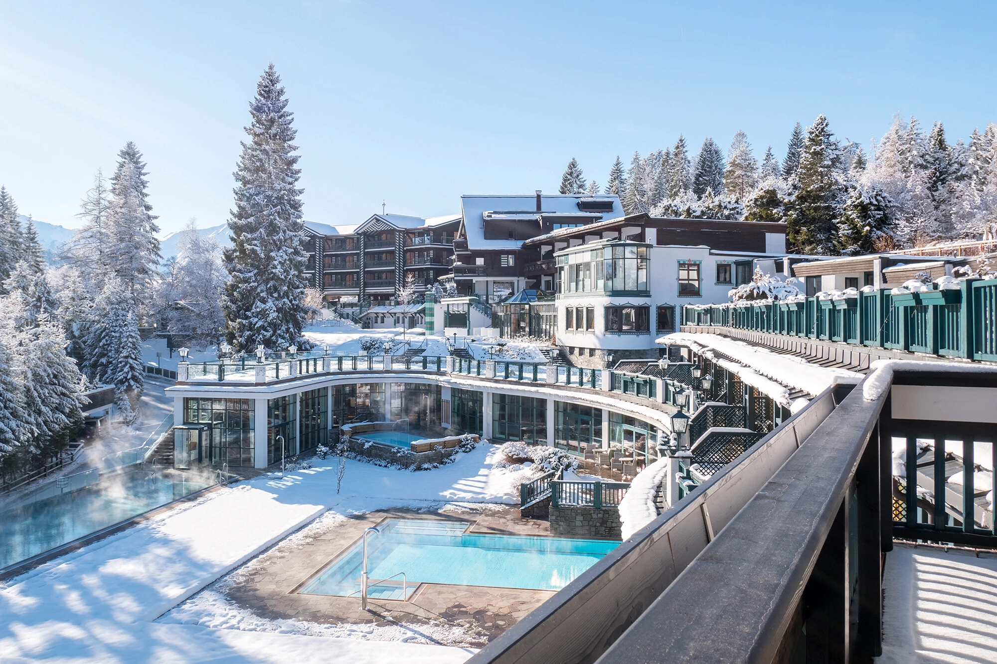 Hotel Sacher Seefeld im Winter bei Tag – Blick vom Balkon auf die verschneite Poolanlage