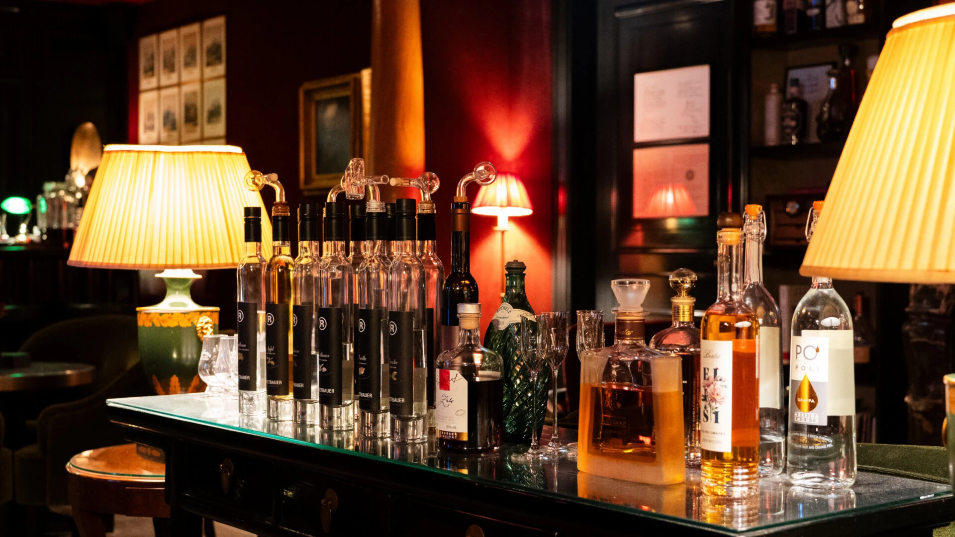 Eine Auswahl an Premium-Spirituosen auf einem dunklen Holztisch in einer stimmungsvoll beleuchteten Bar.