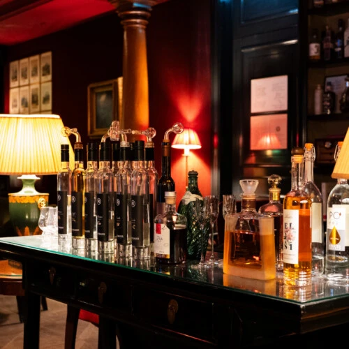 Eine Auswahl an Premium-Spirituosen auf einem dunklen Holztisch in einer stimmungsvoll beleuchteten Bar.