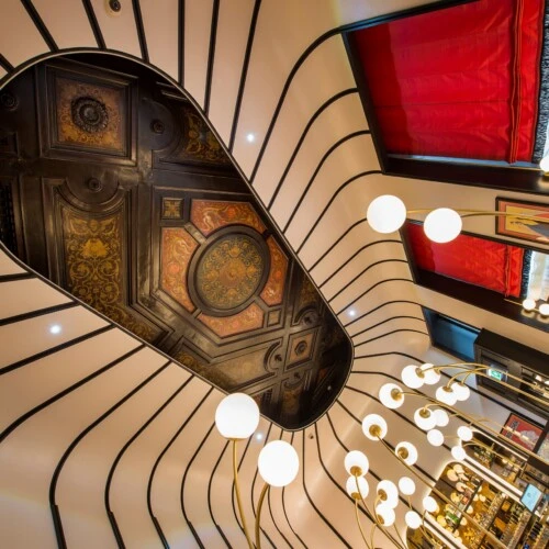 Extravagantes Decken-Design mit einem antik anmutenden, kunstvoll bemalten Deckenelement im Zentrum, umrahmt von modernen, geschwungenen Linien in Schwarz-Weiß-Kontrast