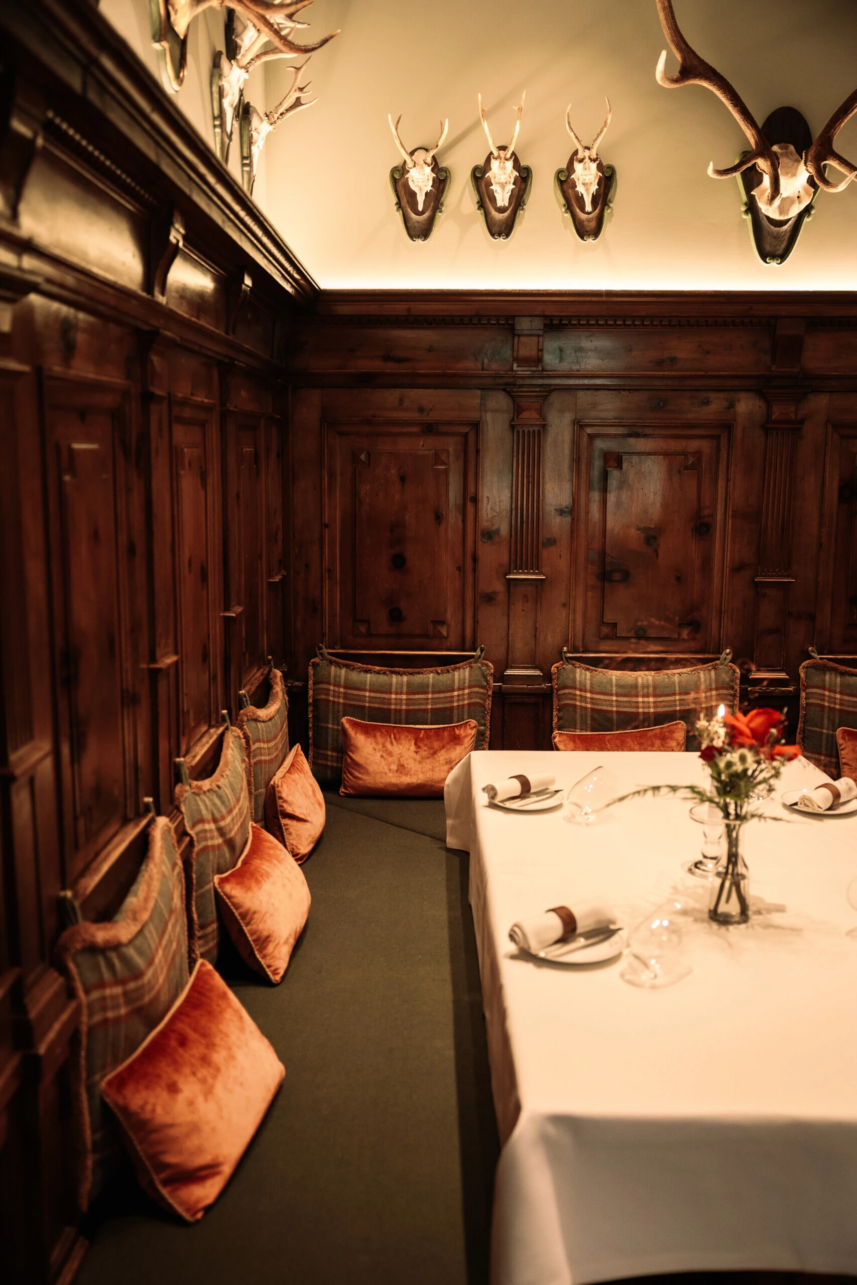 Restaurant Zirbelzimmer. Gemütliche Restaurantnische mit Holzvertäfelung und Hirschgeweihen an der Wand