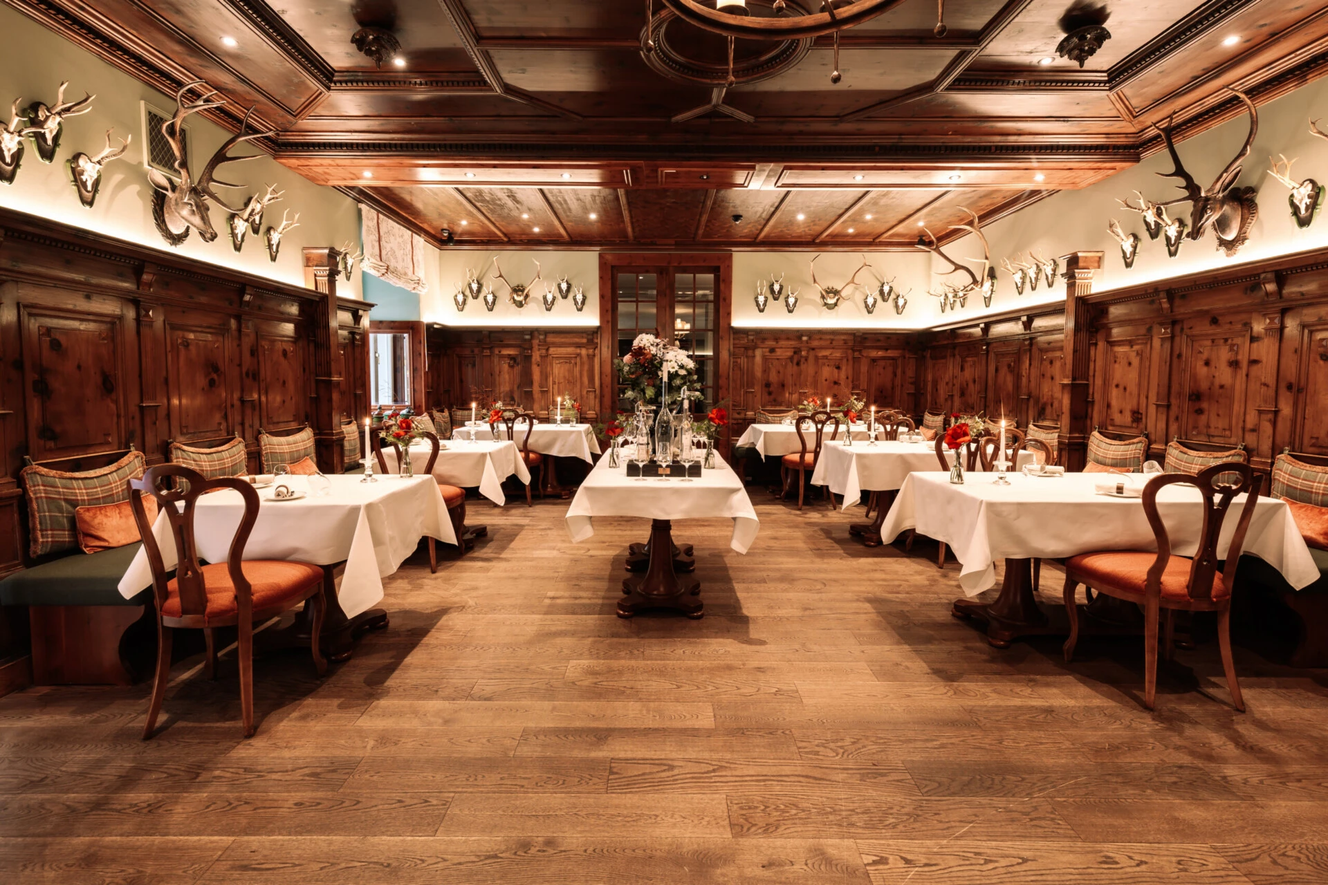 Restaurant Zirbelzimmer. Eleganter Speisesaal mit Holzeinrichtung, gedeckten Tischen und warmem Licht.