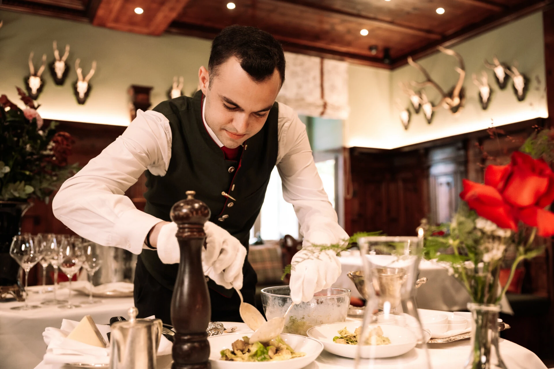 Restaurant Zirbelzimmer. Kellner bereitet ein Gericht am Tisch zu.