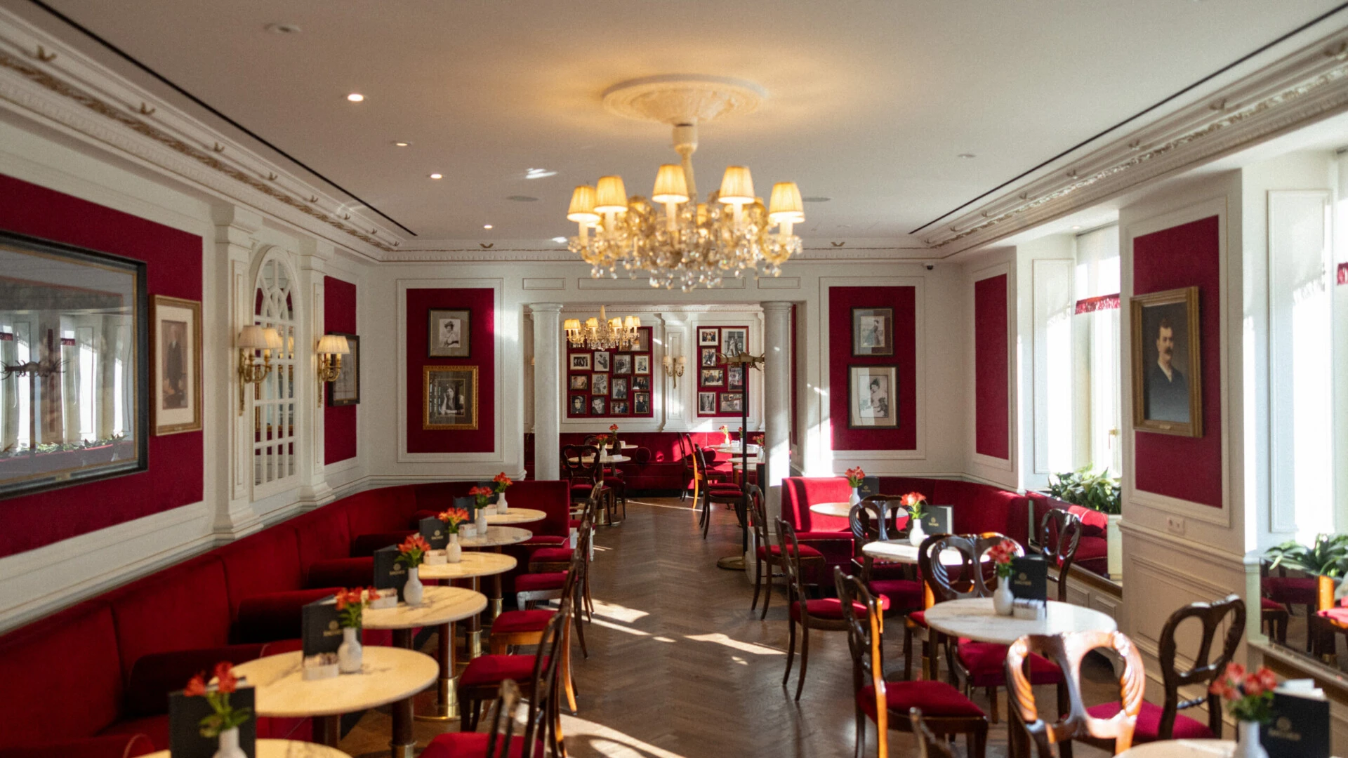 Elegantes Café im Hotel Sacher Salzburg mit roten Samtbänken, Marmortischen und Kronleuchter