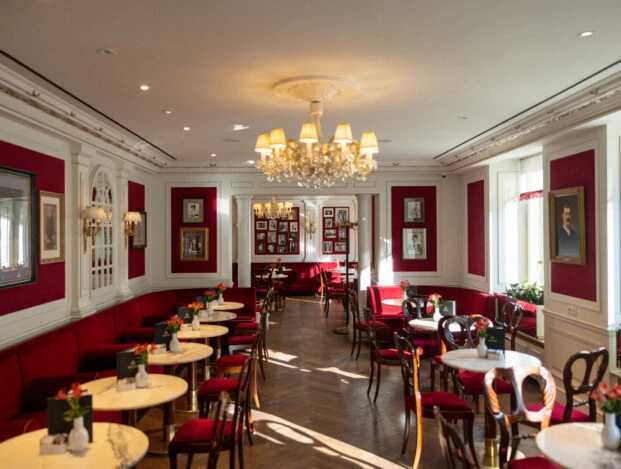 Elegantes Café im Hotel Sacher Salzburg mit roten Samtbänken, Marmortischen und Kronleuchter