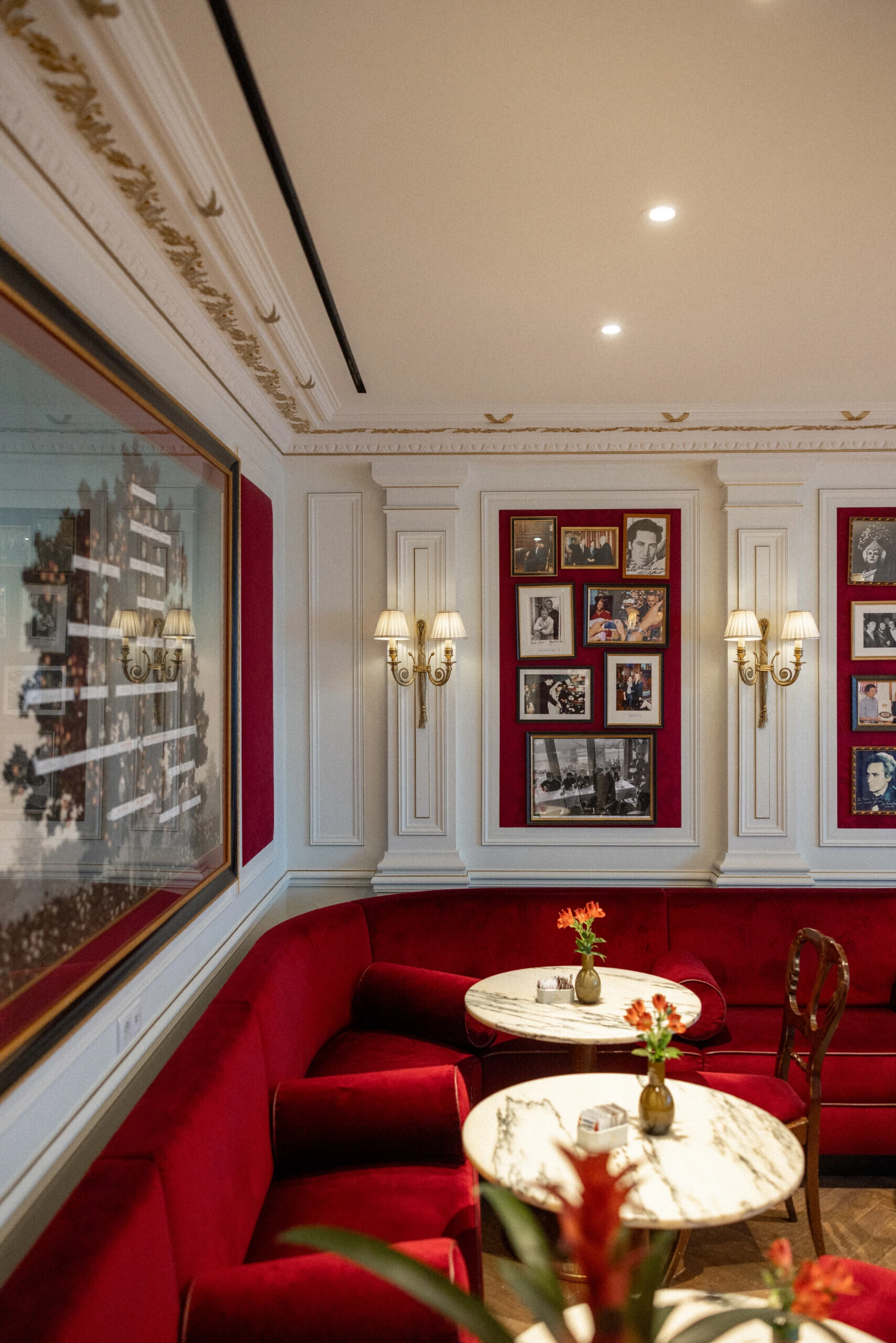 Detailansicht einer Sitzecke im Café Sacher Salzburg mit roten Polstern und gerahmten Fotografien