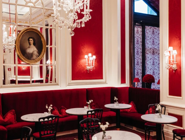 Stilvolles Café Sacher Wien mit roten Samtbänken, Marmortischen, Kronleuchter und klassischer Wandgestaltung