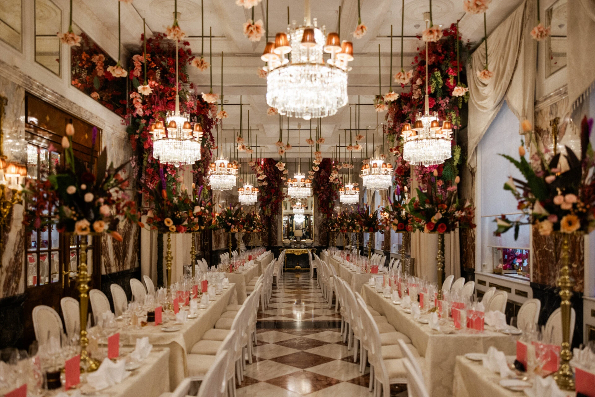 Elegantly decorated event hall with long banquet tables, lavish floral arrangements, and crystal chandeliers at Hotel Sacher