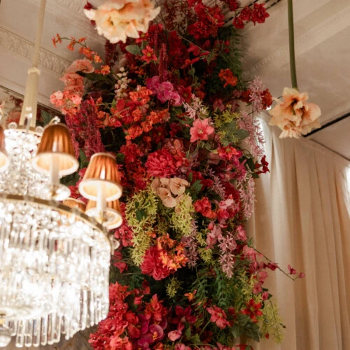 Opulente florale Dekoration mit hängenden Blüten und Kristalllüster im festlich geschmückten Marmorsaal des Hotel Sacher