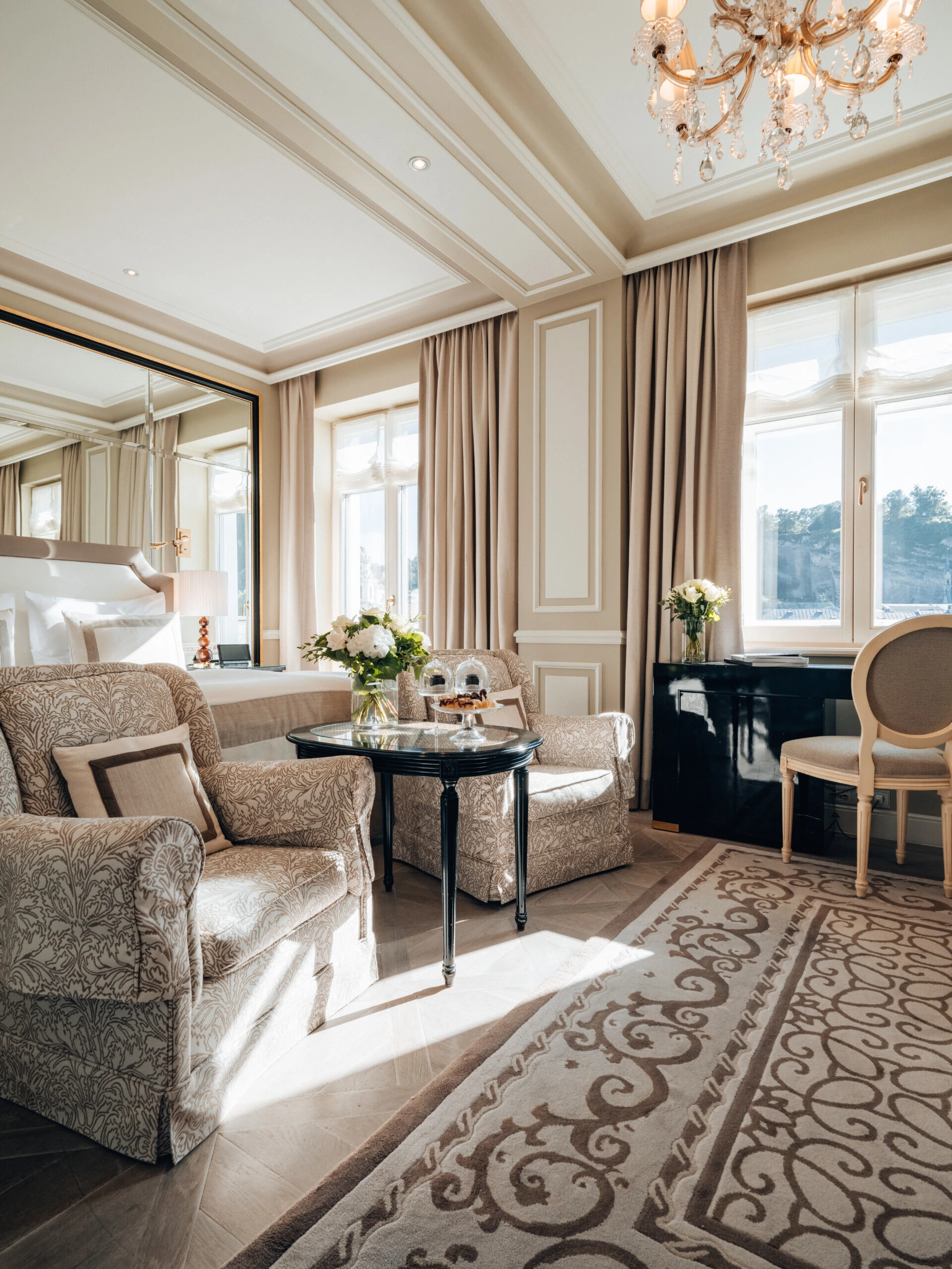 Deluxe Zimmer mit Ausblick im Hotel Sacher Salzburg mit elegantem Sitzbereich, klassischen Möbeln und großen Fenstern mit Aussicht auf die Salzburger Altstadt