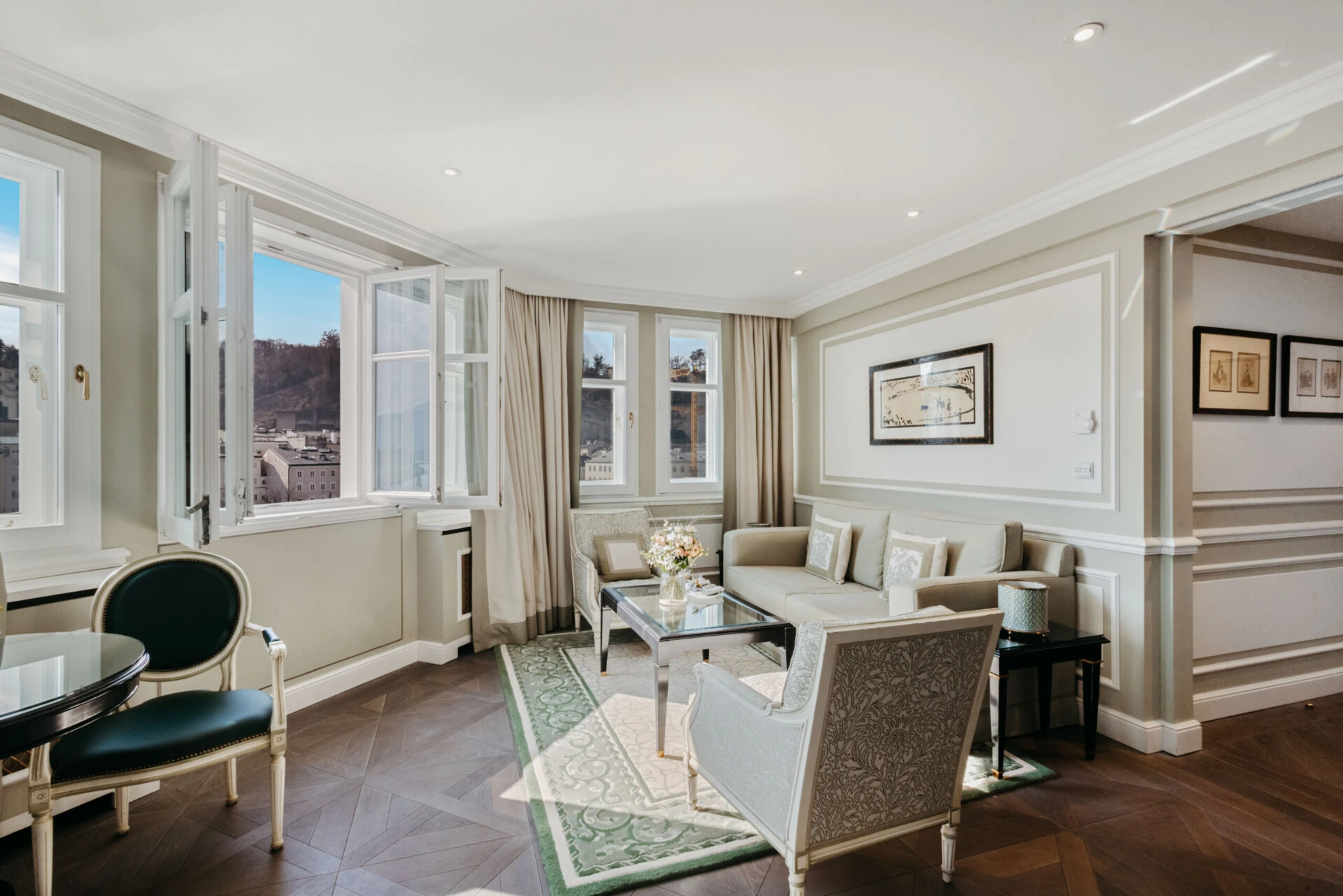 Wohnbereich der Signature Suite mit Ausblick im Hotel Sacher Salzburg, mit eleganter Sitzecke, großen Fenstern und Blick auf Salzburg