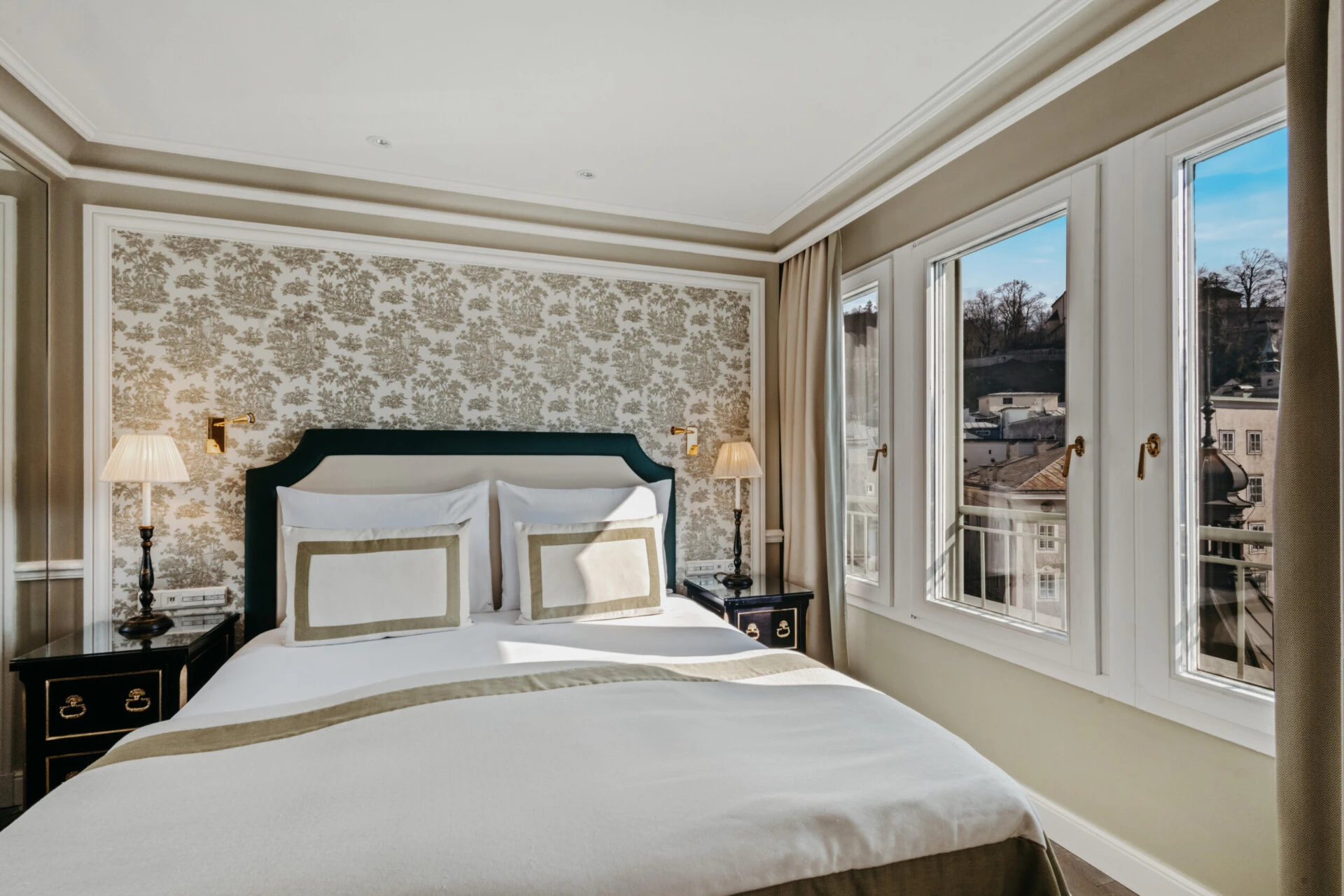 Schlafzimmer der Signature Suite mit Ausblick im Hotel Sacher Salzburg, mit elegantem Bett und großen Fenstern zur Salzburger Altstadt
