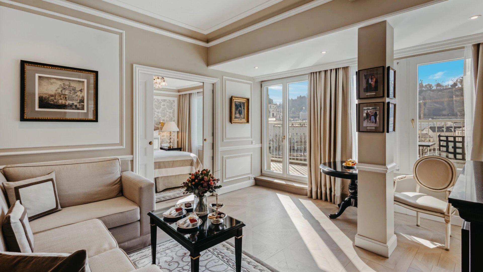 Wohnbereich der Signature Suite mit Balkon im Hotel Sacher Salzburg, mit Sofa, elegantem Tisch und Blick auf Salzburg