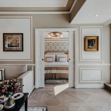 Wohnbereich der Signature Suite mit Balkon im Hotel Sacher Salzburg, mit Sofa, Blick ins Schlafzimmer und großen Fenstern