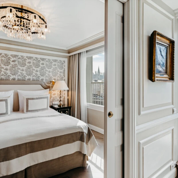 Schlafzimmer der Signature Suite mit Balkon im Hotel Sacher Salzburg, mit elegantem Bett, Kristalllüster und Balkonblick