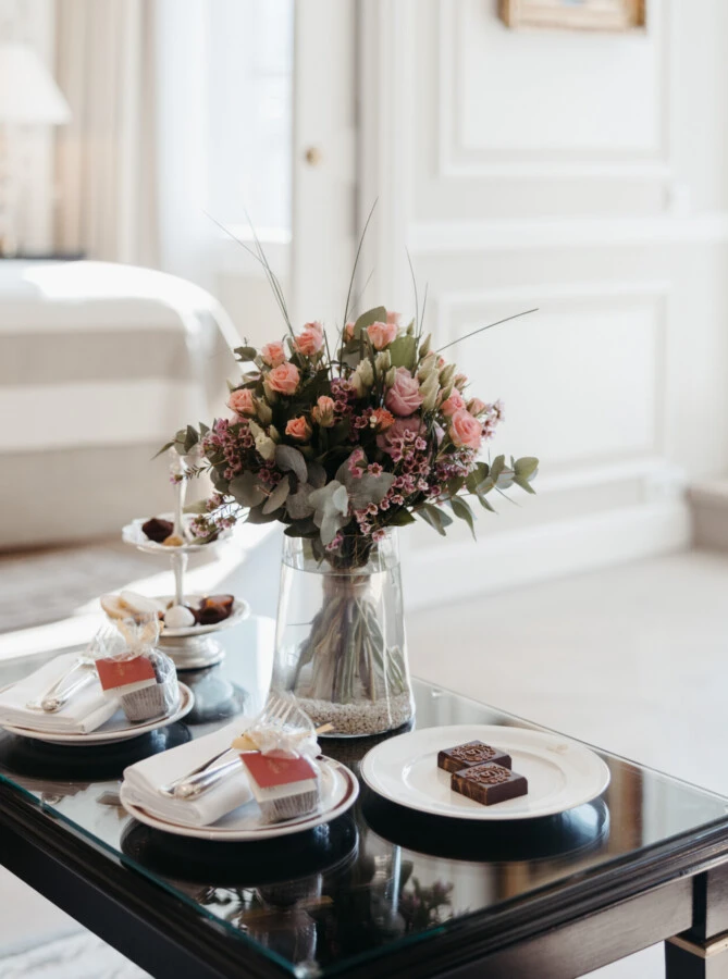 Detailaufnahme des Couchtischs in der Signature Suite mit Balkon im Hotel Sacher Salzburg, mit Blumenstrauß und kleinen Süßspeisen