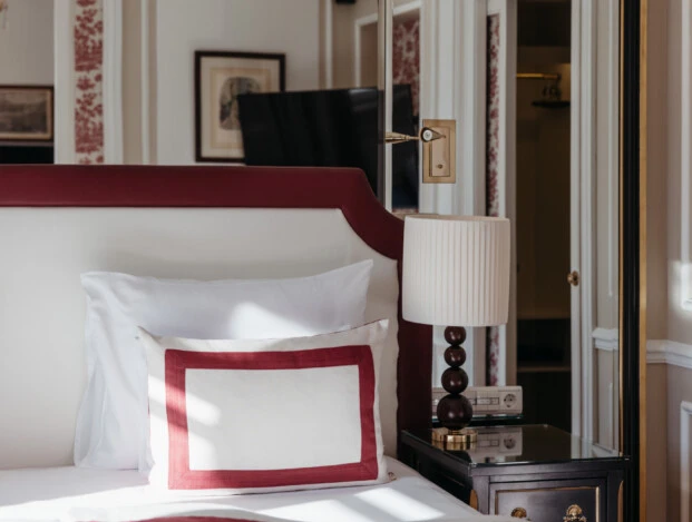 Nahaufnahme des Betts in der Familiensuite mit Ausblick im Hotel Sacher Salzburg, mit roten Designdetails und klassischem Interieur