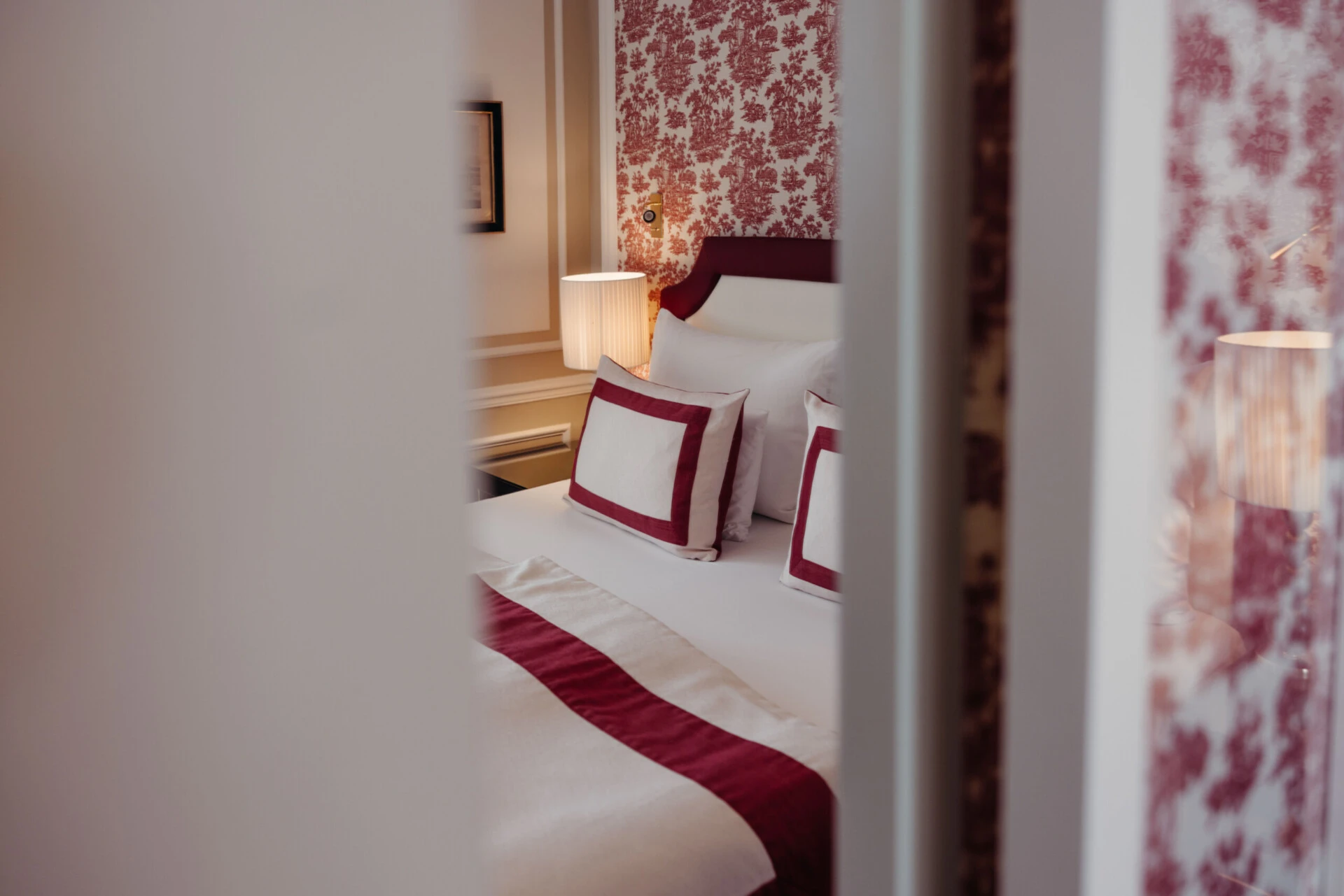 Nahaufnahme des Betts in der Family Suite mit Ausblick im Hotel Sacher Salzburg, mit roten Designdetails und klassischem Interieur